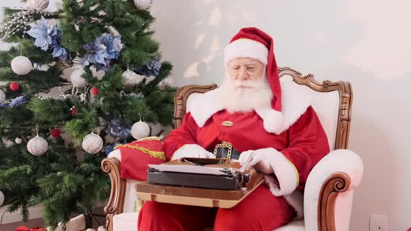 Santa Claus writing on an old typewriter. Concept of letters, writing down an idea or names.