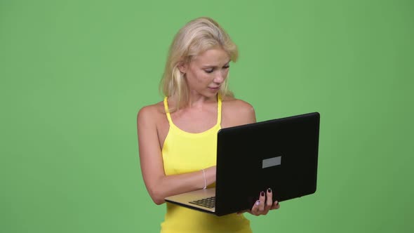 Young Happy Beautiful Blonde Woman Using Laptop Against Green Background