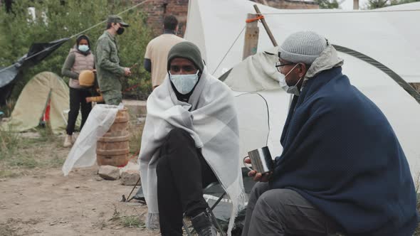 Two Immigrants in Face Masks Talking at Refugee Camp alt