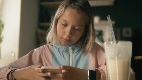 Beautiful Kid Latina Girl in Sitting in Cafe Counter and Drinking Milkshake While Taking Cute Photos alt