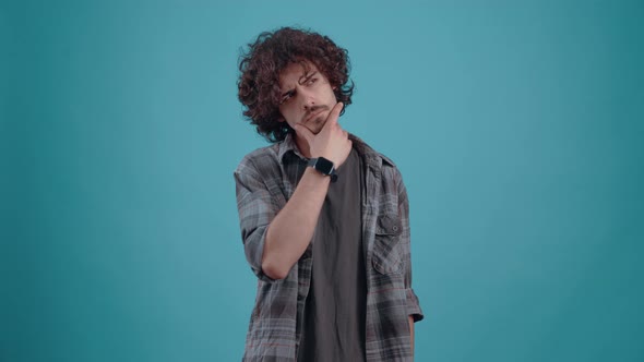 The Young Curlyhaired Hipster Thinks Looking to the Right with His Hand on His Chin alt