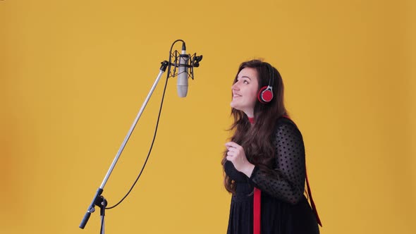 A woman in classical dress at the recording studio sing lyrical song into a microphone alt