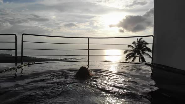 Aerial Top View of Slim Young Woman in Black Bikini Relaxing in Swimming Pool on Tropic Garden Villa