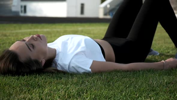 Young Asian Pretty Female in Black Leggings Working Out Outdoors on Green Lawn