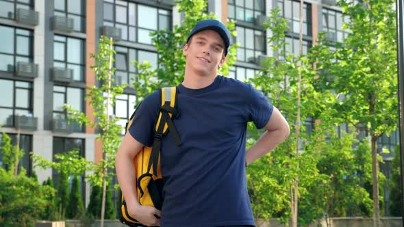 Portrait Smiling Man Courier Food Delivery Puts on Thermal Backpack Looks Camera alt