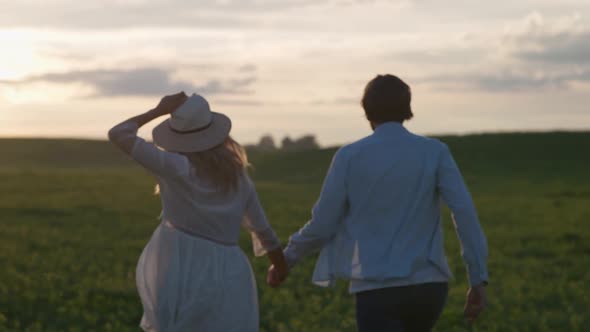 Sunset on a Countryside Young Couple in Nature Man and a Woman are Running Through a Field of alt