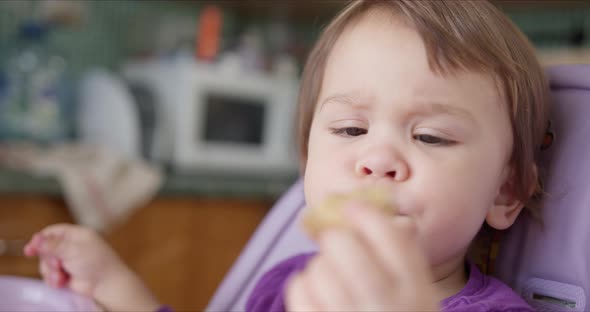 Baby Eating Pancake with His Hands and Sitting in Child's Seat. alt