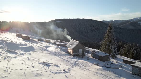 Flying Over Log Cabin Hut With Smoke Coming Out of a Chimney 