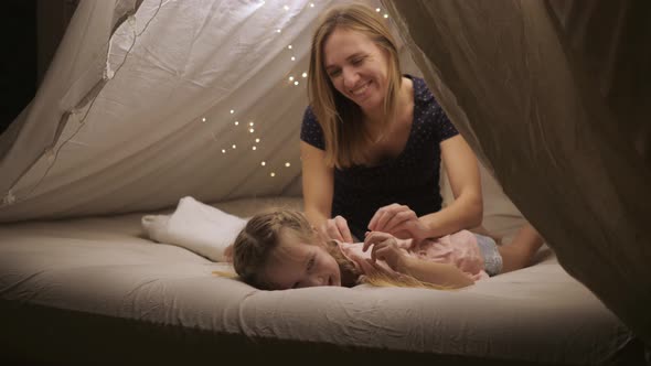 Happy Mom Gives Her Daughter a Back Massage in a Makeshift Tent at Home They Smile and Laugh