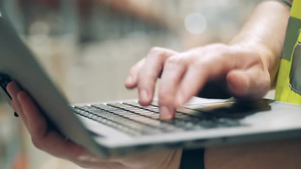 Close Up of Laptop Keyboard with a Male Employee Typing on It alt