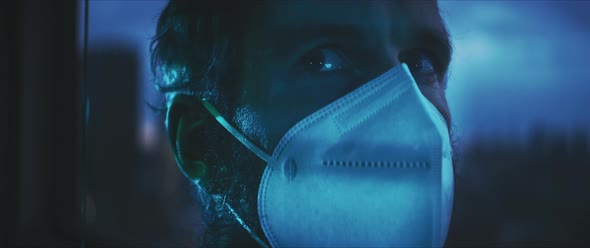 Man in a face mask looking outside alt