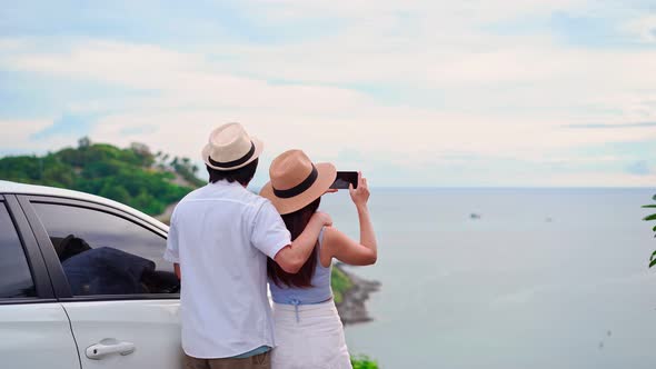 Young couple traveler looking at the beautiful sea view with their car while traveling