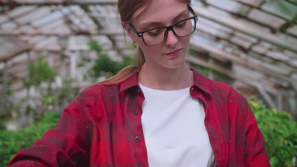 Girl with Glasses Sprays Plants From a Splash or Spray