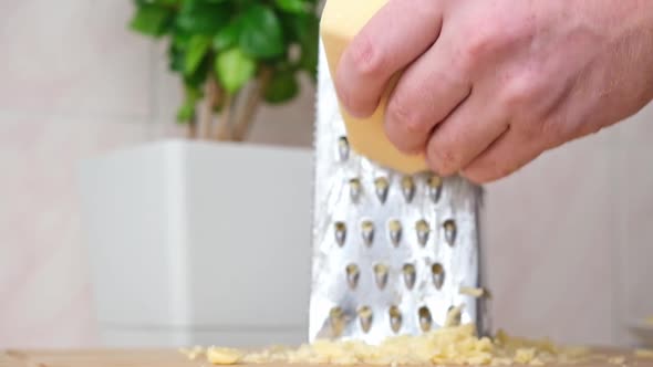 A Man Rubs Cheese on Metal Grater for Freezing and Further Cooking Pizza Pasta