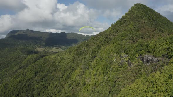 Aerial view of a person doing paragliding among the mountain, Mauritius. alt