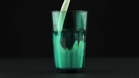 Milk Pouring Into Faceted Green Glass Close Up Isolated on Black Background Slow Motion alt