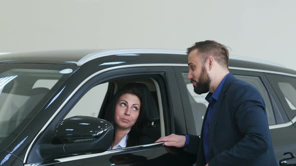 Pretty Young Casual Couple Choosing Car in Dealership