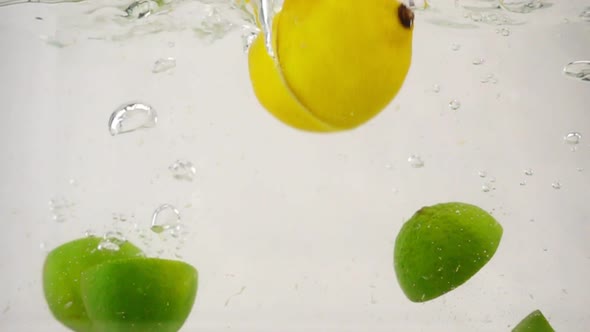 Juicy Halves of Lyme Fall Into the Water with Bubbles and Splashes, Slow Motion Close-up alt