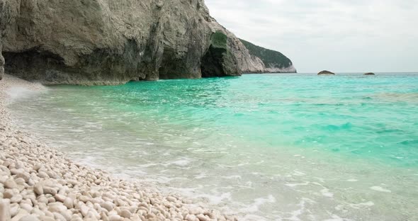 Waves of blue sea crushing on beach with white pebbles. alt