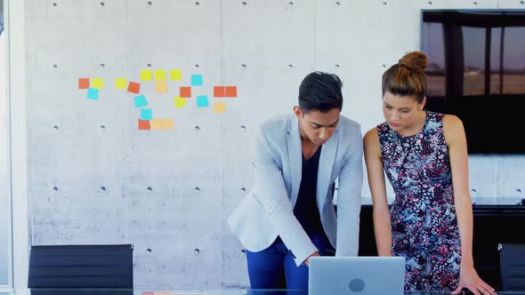 Business executives discussing over laptop  alt