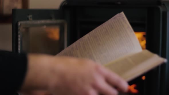 A guy reading a book in front of the fire place alt