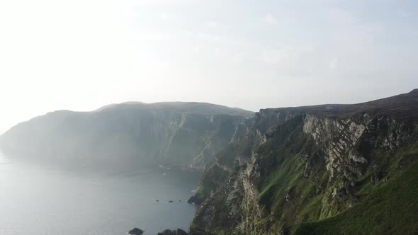 Two people sitting on the cliff looking at the mountain range at Horn Head in Donegal Ireland alt