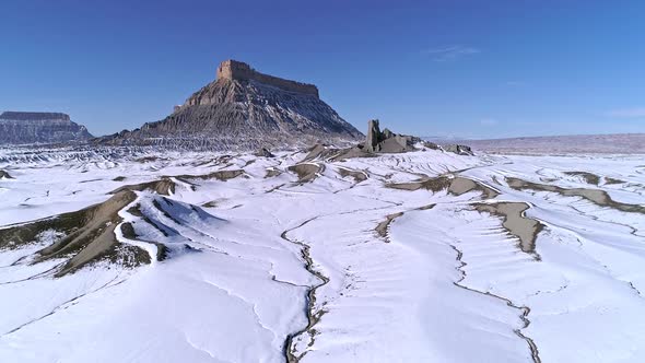 Aerial view flying towards Factory Butte with snow across the landscape alt