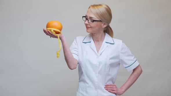 Nutritionist Doctor Healthy Lifestyle Concept - Holding Organic Grapefruit Fruit and Measuring Tape alt