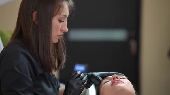 Side View Portrait of Professional Beautician Tattoo Master Doing Permanent Eyebrow Makeup for alt