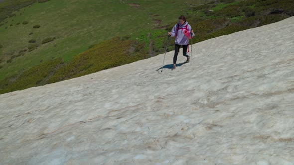 Girl Hiker Walking Carefully on Snowy Hillside alt