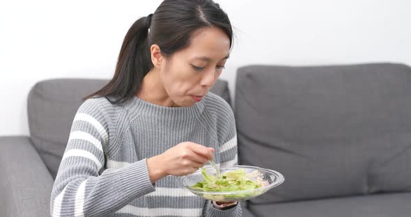 Woman eating salad at home alt