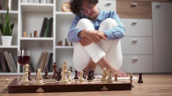 Young Woman Playing Chess On The Floor At Home. A European Girl Plays Chess With A Glass Of Wine alt