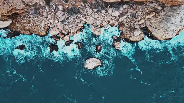 Aerial Top View of Waves Break on Rocks in a Blue Ocean alt