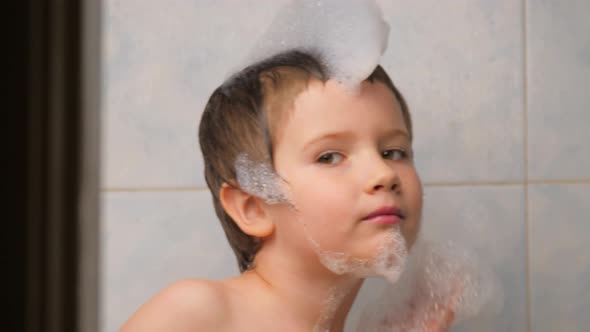 Kid Playing with Foam in Bathroom. Happy Boy Taking a Bath. Face of Smiling Brown Eye Boy with Foam