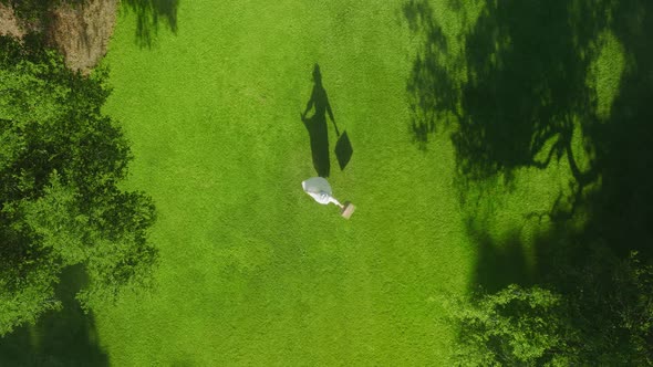 Happy Young Woman Spinning with Picnic Basket in Center of Green City Park alt
