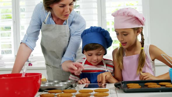Mother and children making cookies in kitchen alt