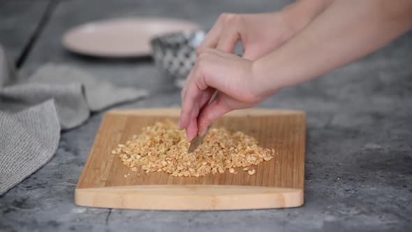 Female Hands Cut Peanuts on a Cutting Board