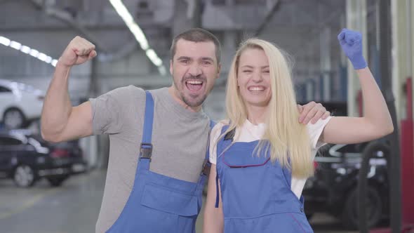 Young Caucasian Man and Woman Showing Strength Gesture, Looking at Camera and Smiling. Professional alt