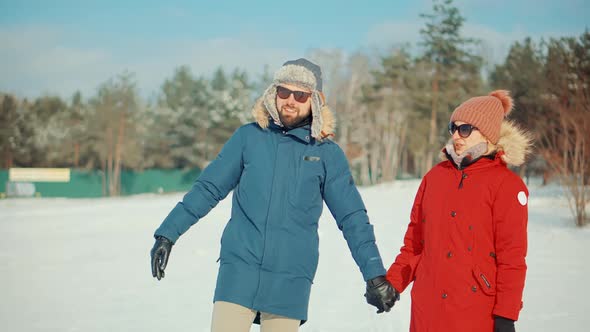 Woman And Man Holding Hands Walking In Parka. Relax Lifestyle Having Fun In Cold Day. Snowy Park. alt
