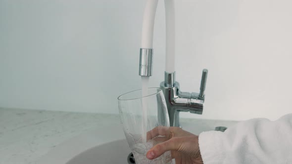 Filling glass by tap transparent mineral water. Fresh and pure home water