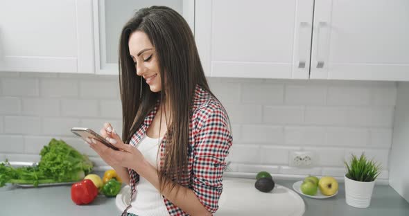 Woman with Smartphone in Kitchen