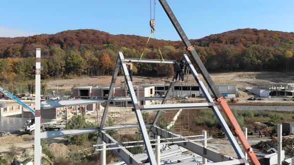 Aerial Shot Installation of a Roof and a Framework From a Metal Construction. Workers Mount the Roof alt