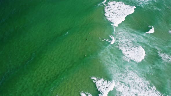 Aerial View of Waves of Emerald Green Ocean Rolling Towards the Shore alt