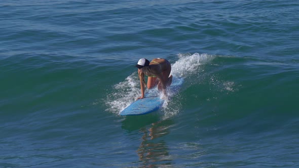 A young woman surfing in a bikini on a longboard surfboard. alt