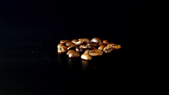 Roasted coffee grains scatter on a black background. Close-up of coffee beans. alt