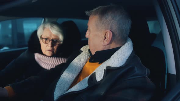 Elderly Couple Looking at Each Other in Shock Realising There Is Police Behind Their Car alt