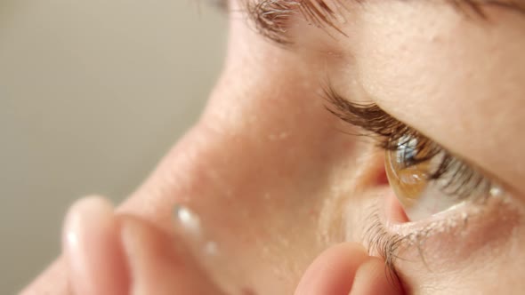 Woman Putting on Contact Lens Closeup Brown Eyes alt