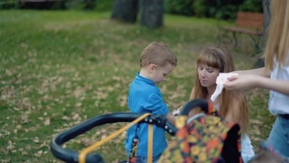 Young Mother and Her Friend Wipe the Faces of Children alt