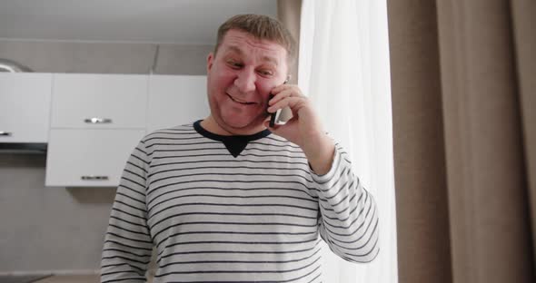 Middleaged Man Speaks on the Phone Speaks Positively Smiles Happily Laughs Jokingly Stands in a alt