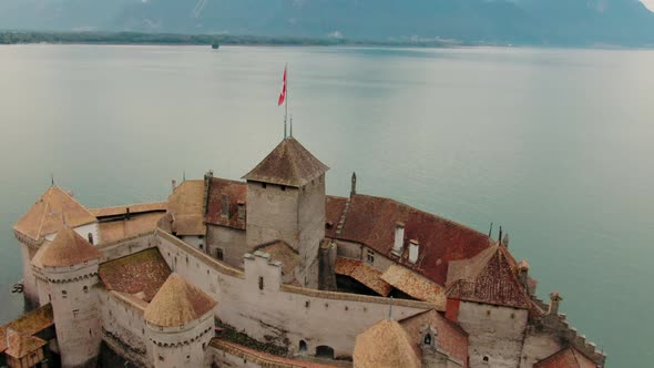 Aerial Panorama of Medieval Chillon Castle with Swiss Flag on Alpine Geneva Lake